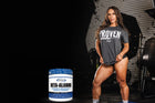 Athletic woman in a gym setting wearing a shirt that says 'PROVEN' while holding a container of beta-alanine supplement, highlighting its benefits for endurance and muscle stamina.
