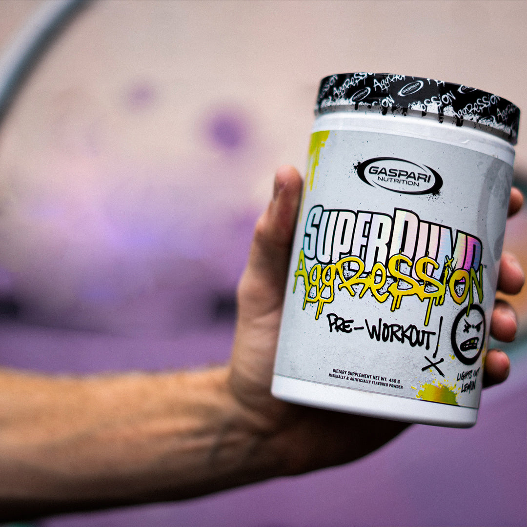 Hand holding Gaspari Nutrition Super Pump Aggression pre-workout container with "Lemon" flavor.